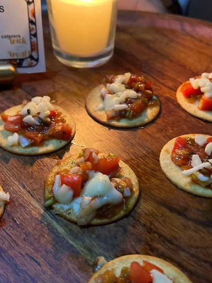 A platter of 'Vampiricious Crackers', which are mini pizzas on a cracker base. These bite-sized treats are perfect for a Halloween party menu, easy to eat while mingling.
