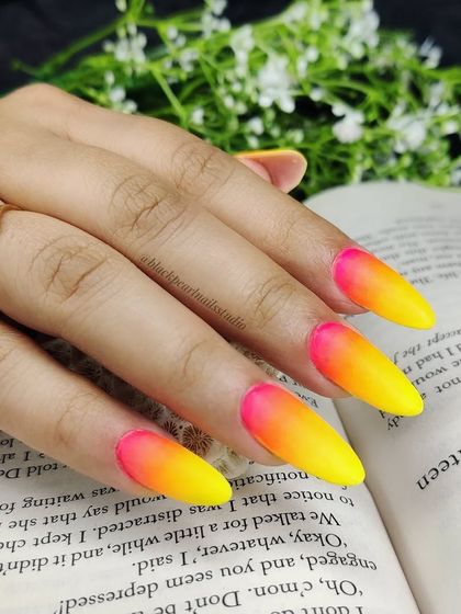 A full look at the vibrant neon ombré nail art, featuring a gradient of hot pink, orange, and yellow. This sizzling trend is perfect for anyone who wants to stand out and shine bright.