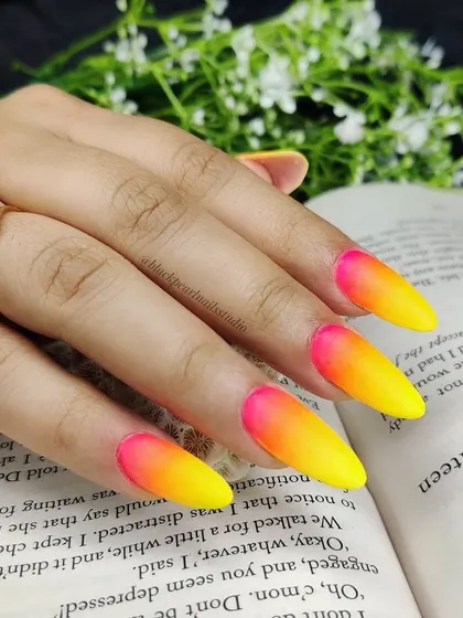 A full look at the vibrant neon ombré nail art, featuring a gradient of hot pink, orange, and yellow. This sizzling trend is perfect for anyone who wants to stand out and shine bright.