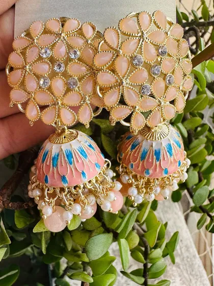 For a soft, pastel look, these peach-colored jhumkas are a great choice. The dome features delicate blue and pink brushstrokes, offering a subtle pop of color.
