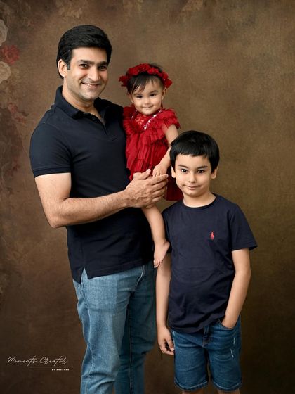 A proud father with his two children. This portrait captures the special bond between a dad, his son, and his baby daughter during her milestone photoshoot.