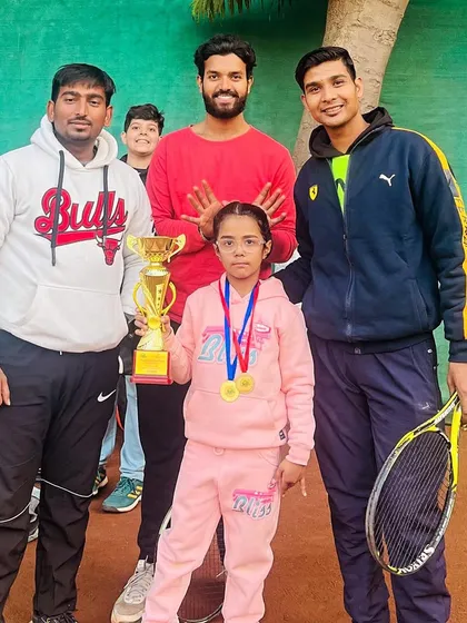 Three of our coaches celebrating with a young U8 champion in her pink tracksuit. This picture captures the supportive team environment we build around our players at our Vikaspuri center.