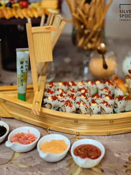 I bring global flavors to your table with artistically presented dishes like this handcrafted sushi boat. It's a perfect centerpiece for birthdays and corporate events, complete with wasabi, soy sauce, and pickled ginger.