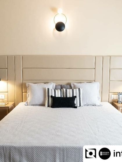 A guest bedroom from the Ekavarna project, designed with a neutral palette and clean lines. The upholstered headboard and modern bedside lamps create a welcoming and comfortable space for visitors.