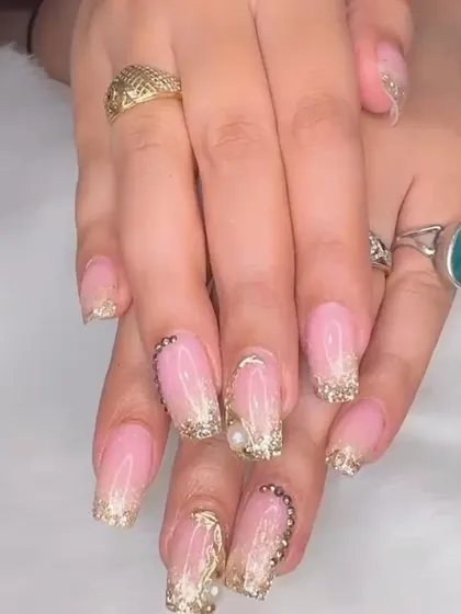 Stunning bridal nails featuring a soft ombré base with extravagant gold glitter, chrome, and pearl embellishments.