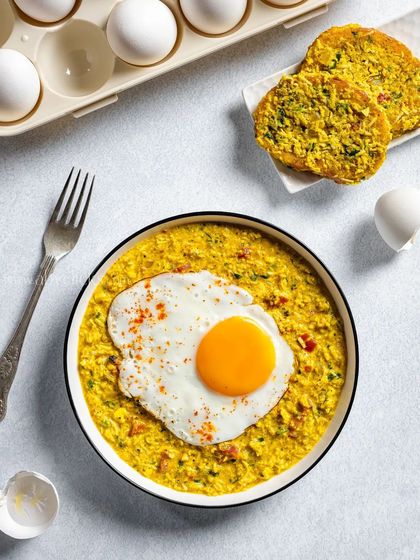 A top-down shot of a bowl of egg bhurji (scrambled eggs) topped with a perfect sunny-side-up.