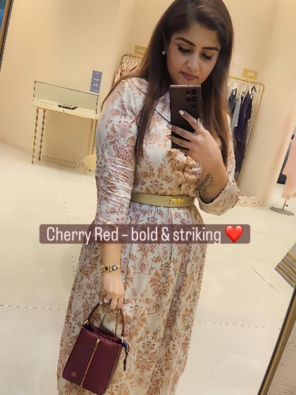 The cherry red bag adds a pop of color and drama to the neutral printed dress.