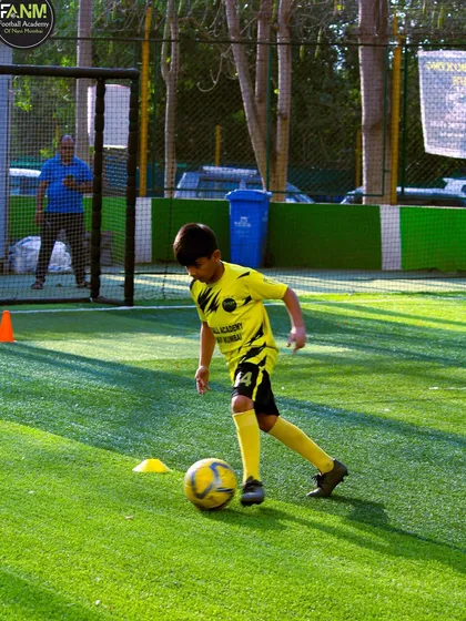 Another focused player works on his dribbling technique under the sun.
