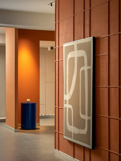 A closer look at the custom wall art and terracotta paneling. The abstract art piece complements the linear grid of the wall, adding a softer, graphic element to the space.