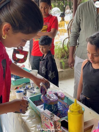An instructor demonstrates the pouring technique to curious young artists at a birthday party, ensuring everyone feels confident to try it themselves.