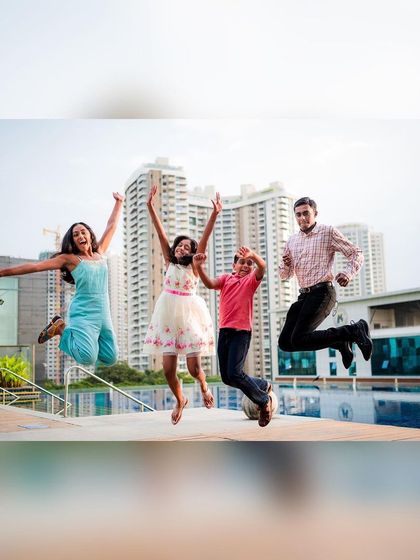 A high-energy family portrait where everyone is jumping in the air against a modern city backdrop. We love creating fun, dynamic shots like this.