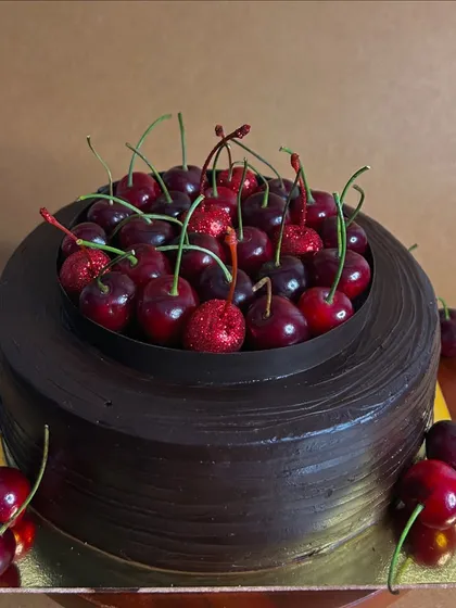Another look at the decadent Cherryoclate cake. It's topped with a whole bouquet of fresh cherries, making it a stunning centerpiece for any celebration.
