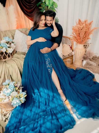 A beautiful couple shot from a boho-themed session. The partner embraces the mom-to-be from behind, both sharing a moment of connection while surrounded by pampas grass and soft textures.