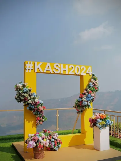 The vibrant yellow frame of the selfie booth stands out beautifully against the blue sky, making it an irresistible photo opportunity.