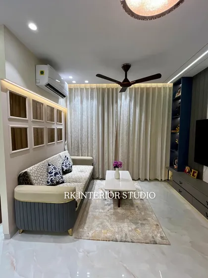 This living room shows a comfortable sofa with custom cushions and a modern TV unit with a display shelf. The wall behind the sofa features decorative niches, adding a unique design element.