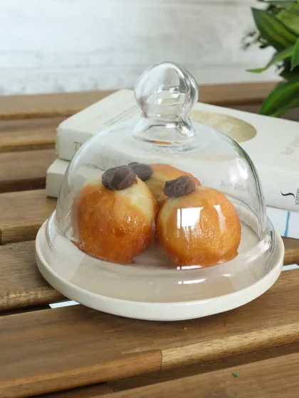 A simple yet elegant ceramic cloche with a glass dome. This versatile piece is perfect for keeping pastries fresh or for creating a beautiful display on your countertop.