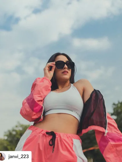 A low-angle shot emphasizing the cool, relaxed attitude of the athleisure look. The oversized sunglasses complete this modern, street-style inspired outfit.