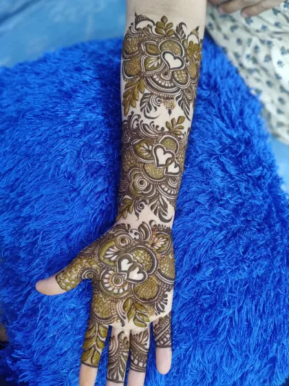A modern and romantic take on bridal mehndi, featuring interlocking hearts as a central motif throughout the arm.