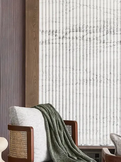 A detail shot showing the textural contrast between the fluted Satvario marble wall, the smooth painted arch, and the cane-backed lounge chair. This interplay of materials is a key feature of the design.