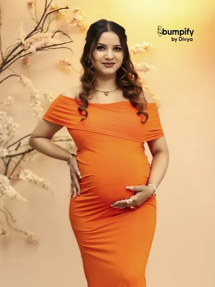 A close-up of the mom-to-be in the orange gown, showing her radiant smile. This is a perfect example of a happy and confident maternity photo.