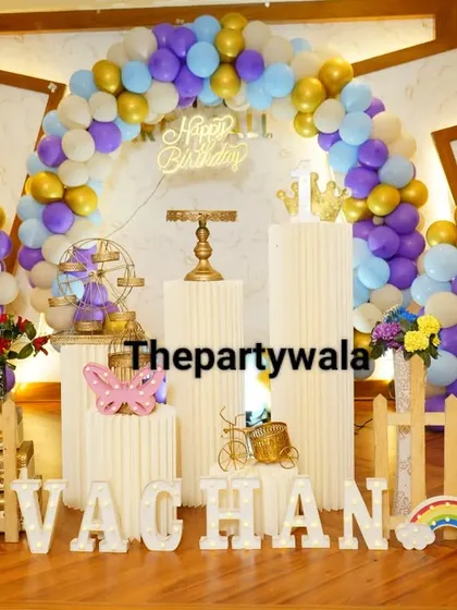 A grand setup with a purple, blue, and gold balloon arch. The life-size photo cutouts of the birthday boy are a fantastic personal touch.