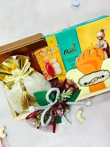 This Rakhi gift hamper is presented in a simple yet elegant wooden tray. It includes a mix of traditional sweets and a rakhi, adorned with a beautiful floral decoration.