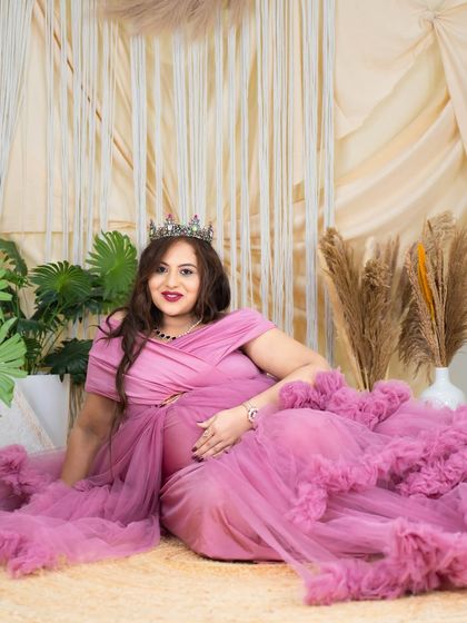 A relaxed yet regal portrait. The mom-to-be is lying on the floor of our boho studio in a beautiful pink gown, looking confident and serene.