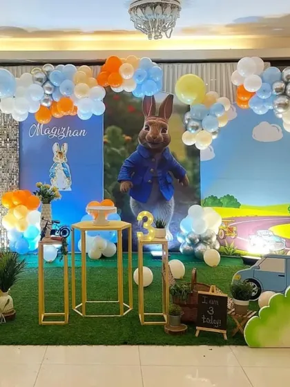 A charming Peter Rabbit theme with a countryside backdrop. The setup uses a green grass floor and gold pedestals to create a garden party feel.