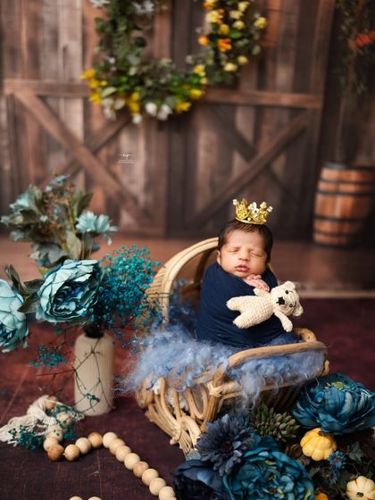 A little prince in his rustic cradle, complete with a tiny crown and a teddy bear friend.