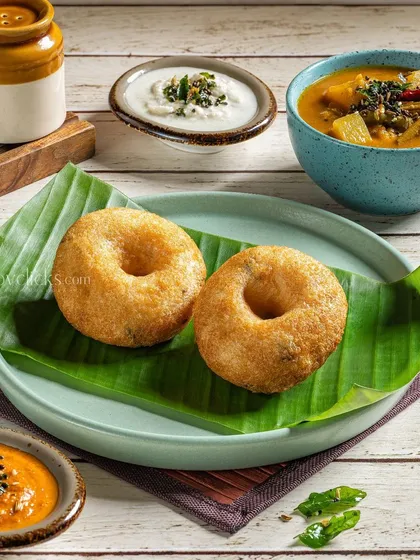Crispy Medu Vadas served on a banana leaf with sambar and chutney for Gulab Sweets.
