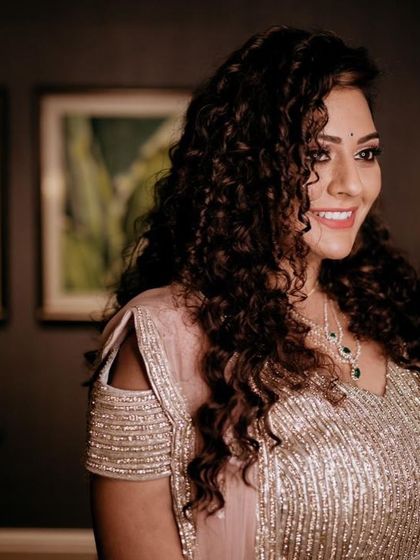 A candid shot of a bride with beautiful curly hair. Her makeup is natural and glowing, perfect for her reception.