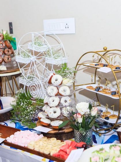A beautiful dessert table with a Greece-inspired aesthetic, featuring donut towers, pastries, and a chocolate fondue station.