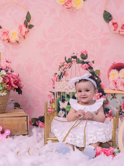 A magical first birthday setup for a little princess. Surrounded by pink flowers, clouds, and a unicorn, this baby girl is the star of her own fairytale.