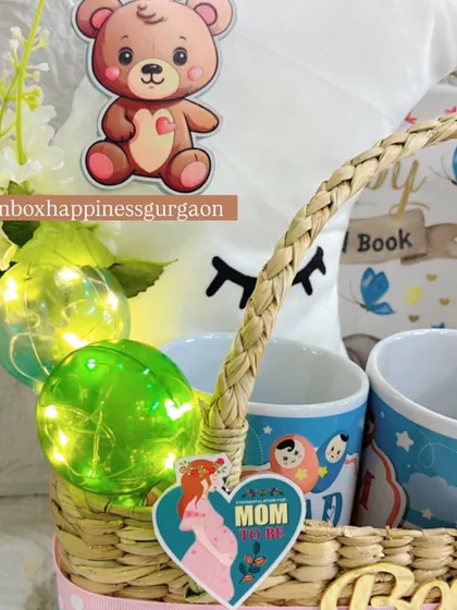 A close-up on the charming details of the moon-themed hamper, including the glowing decorative balls, a teddy bear sticker, and a "MOM" heart tag.