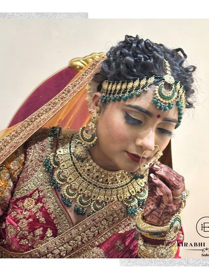 A traditional bridal look featuring a beautiful matha patti with green beadwork. The eye makeup is done in warm tones to match the rich colors of her wedding attire.