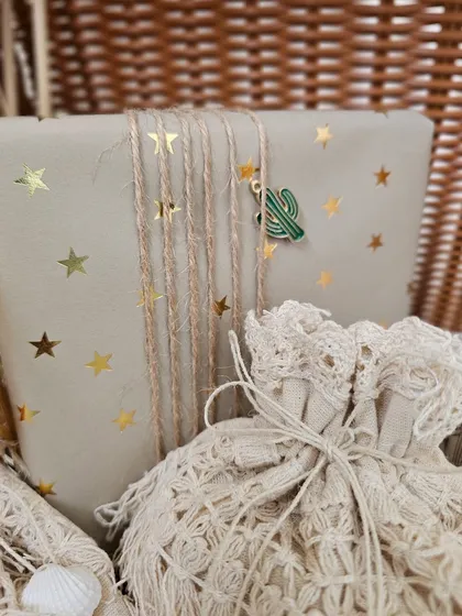 A close-up of a gift from a boho-themed hamper. I love the combination of the gold-starred kraft paper, jute twine, and a cute little cactus charm.