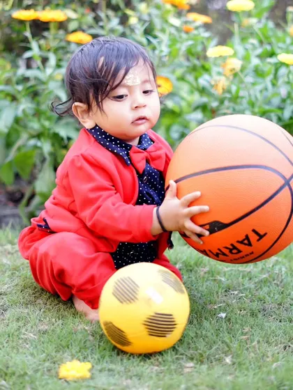 Capturing the action as a young boy plays with a basketball in a garden setting, showing his concentration and engagement.