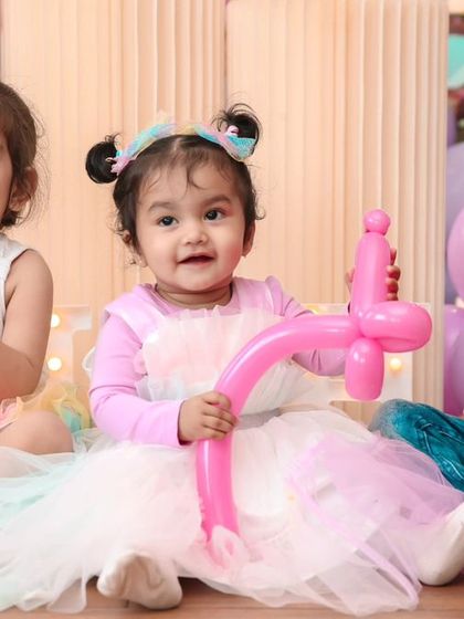 Friends celebrating together. This shot captures the social side of a birthday party, with kids enjoying the activities and making memories. A balloon artist created the fun pink balloon sword for the birthday girl.
