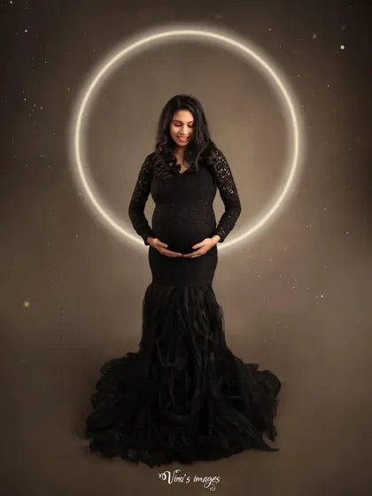 A celestial-themed portrait. The glowing halo behind the mother-to-be gives her an angelic aura, while the black gown provides a timeless and elegant silhouette.
