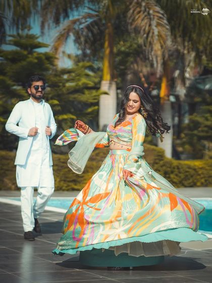 A beautiful twirl by the bride at her poolside Mehendi. Her colorful lehenga and joyful expression perfectly capture the happy and relaxed vibe of the event.