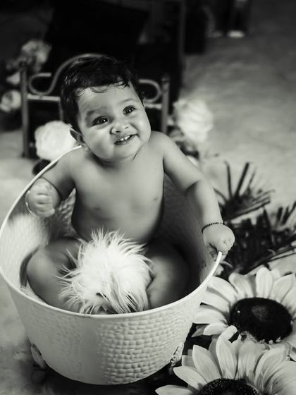 A fun and safe splash time shoot. This black and white photo highlights the joy of our bathtub setup, which includes a classic white tub and surrounding floral props for a touch of whimsy.