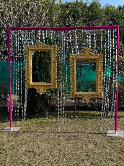 A fun and interactive photo booth for an outdoor event, featuring vintage-style golden frames hanging from a sequin curtain.