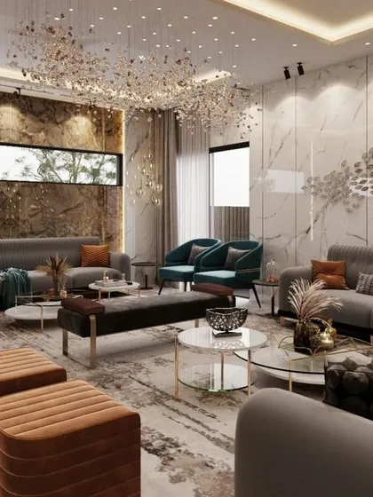 This luxury living room in Lucknow is a study in texture and light. A stunning crystal chandelier illuminates the space, highlighting the rich marble feature wall and the metallic accents on the wall decor, creating a sophisticated and glamorous environment for entertaining.
