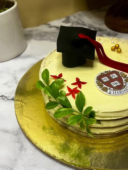 Celebrate academic achievements with a custom graduation cake. This one, for a Harvard grad, features a handcrafted graduation cap, a diploma, and the university crest, making for a proud and delicious centerpiece.