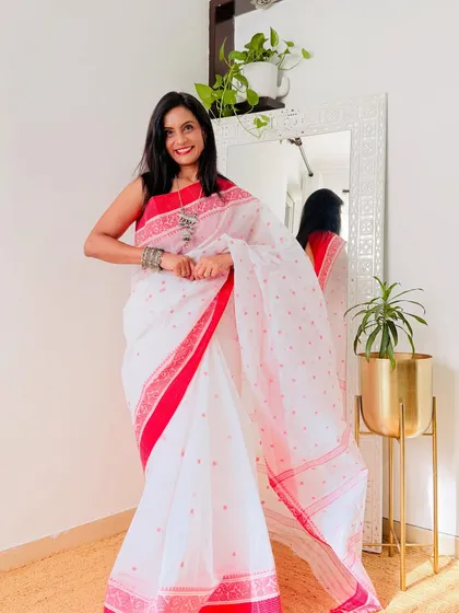 The quintessential Bengali white Tant saree with a red border. This is a timeless and iconic look, perfect for festivals like Durga Puja.