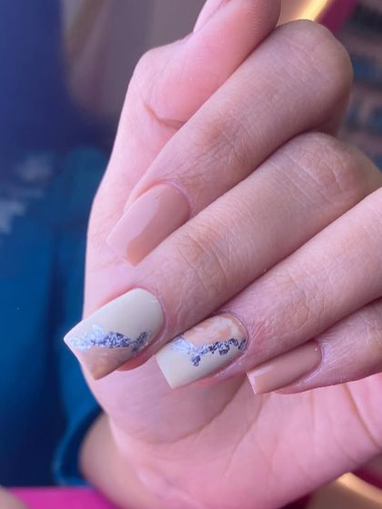 A chic and minimalist design in neutral tones. This set features a mix of solid nude polish with accent nails showcasing a subtle silver foil detail.