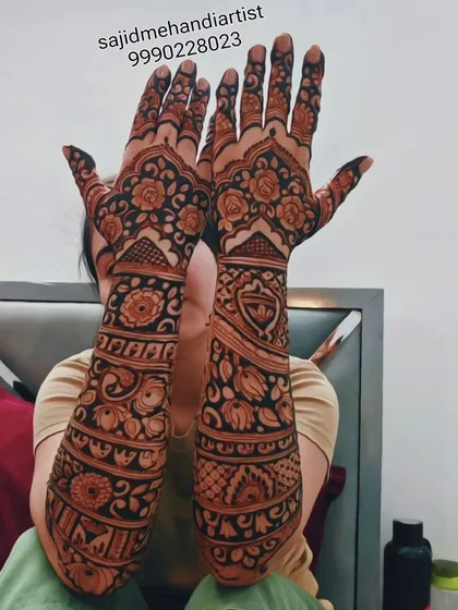 A full-arm design filled with floral and paisley patterns. The artwork extends from the fingers to the elbow, creating a seamless and traditional bridal sleeve of henna.