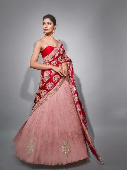 A model showcases a stunning red and pink lehenga saree by Faabiiana, a perfect blend of traditional colors and modern silhouette.