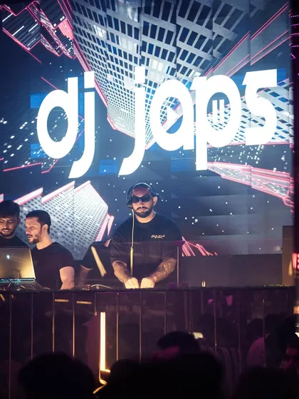 Behind the decks with my logo lit up on the LED screen. This branding adds a professional touch to any stage setup.