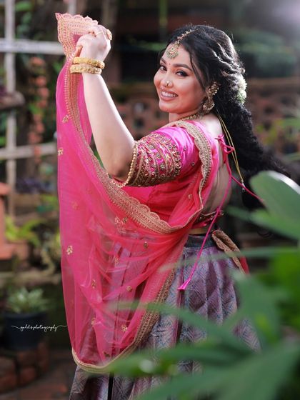 A cheerful and vibrant outdoor shoot featuring a model in a pink and purple half-saree. The playful poses on a swing and the bright colors capture a youthful and joyous spirit.
